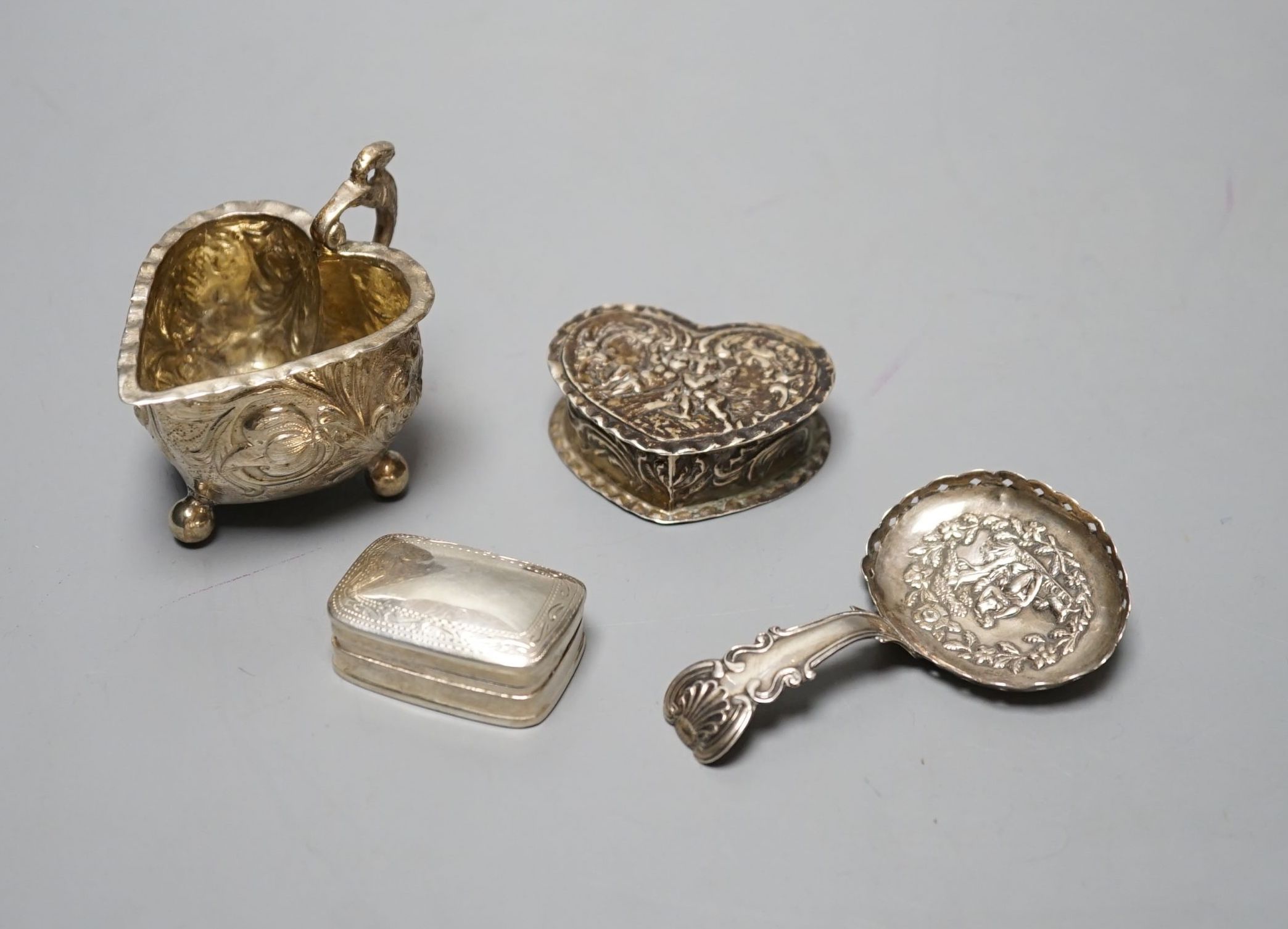 A George III silver caddy spoon, with associated bowl, handle marked for John Bettridge, Birmingham, 1817, 76mm, a late 19thcentury Hanau white metal small jug, an embossed white metal heart shape box and a white metal p